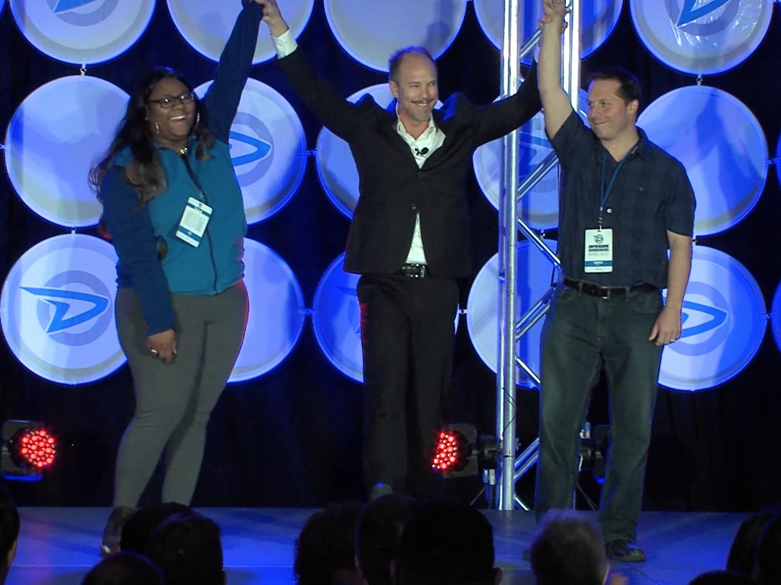 Tim Shurr celebrating two employees on stage at a company event